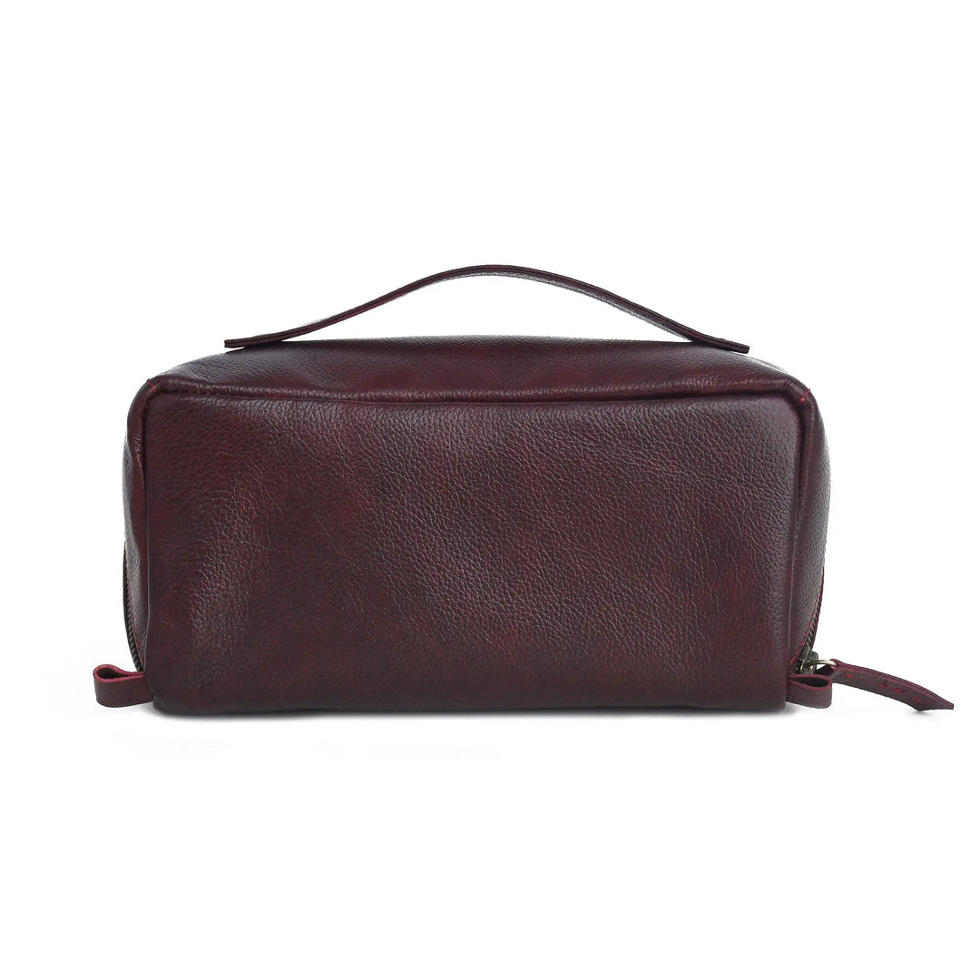 A dark burgundy pebbled leather toiletry bag with a top handle and zipper closure, shown against a plain white background.