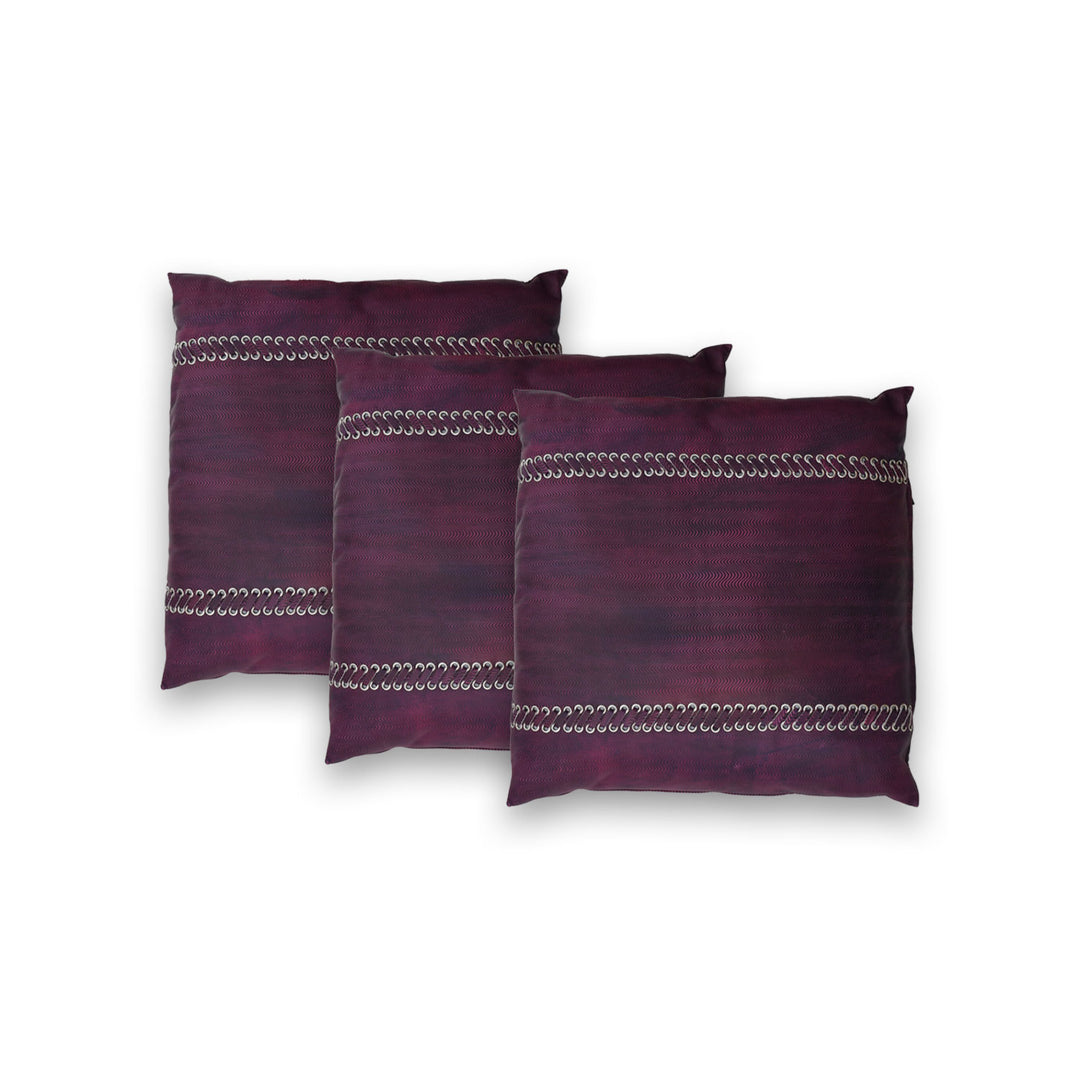 Three purple pillows with decorative patterns on a white background

