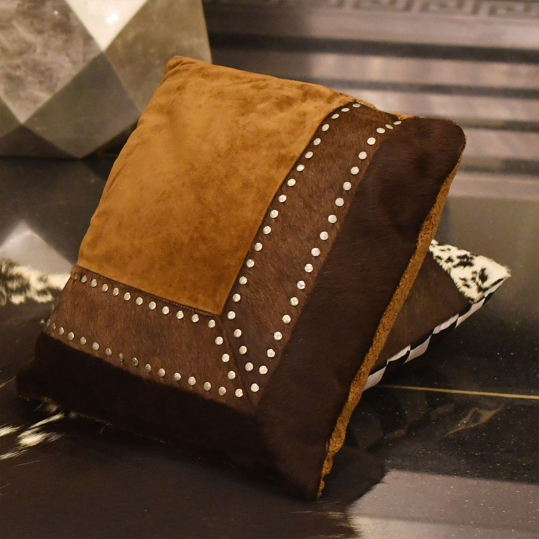 Brown and tan cushion with decorative studs on a reflective surface

