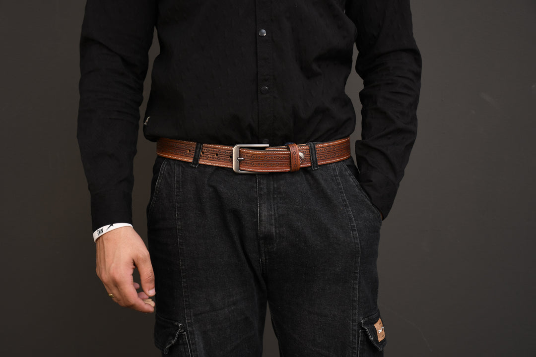 Person wearing a black shirt and dark pants with a brown belt on a gray background