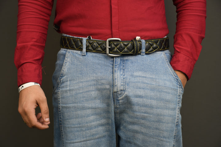 Person wearing a red shirt and blue jeans with a patterned belt on a dark background