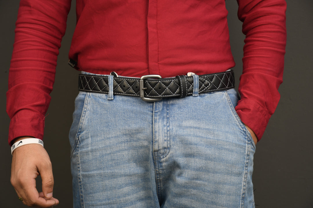 Person wearing a red shirt and blue jeans with a black belt on a gray background