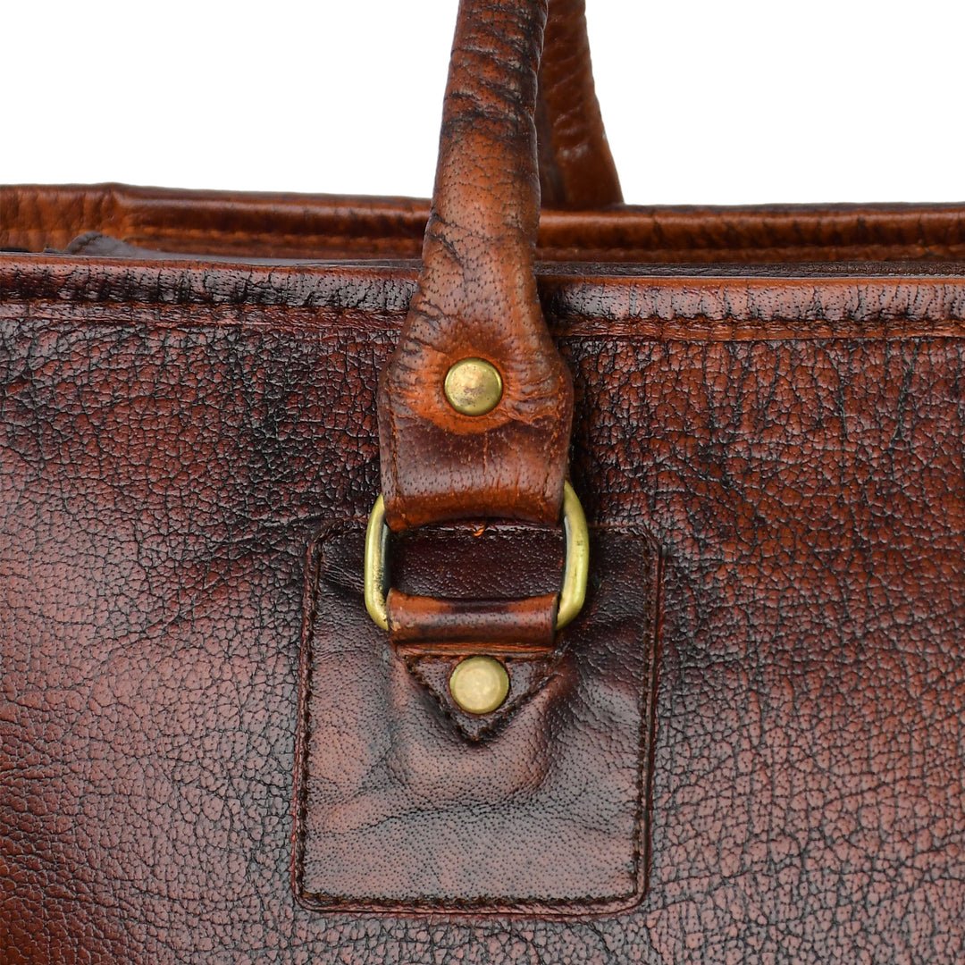 Close-up of a brown leather bag with gold hardware on a white background