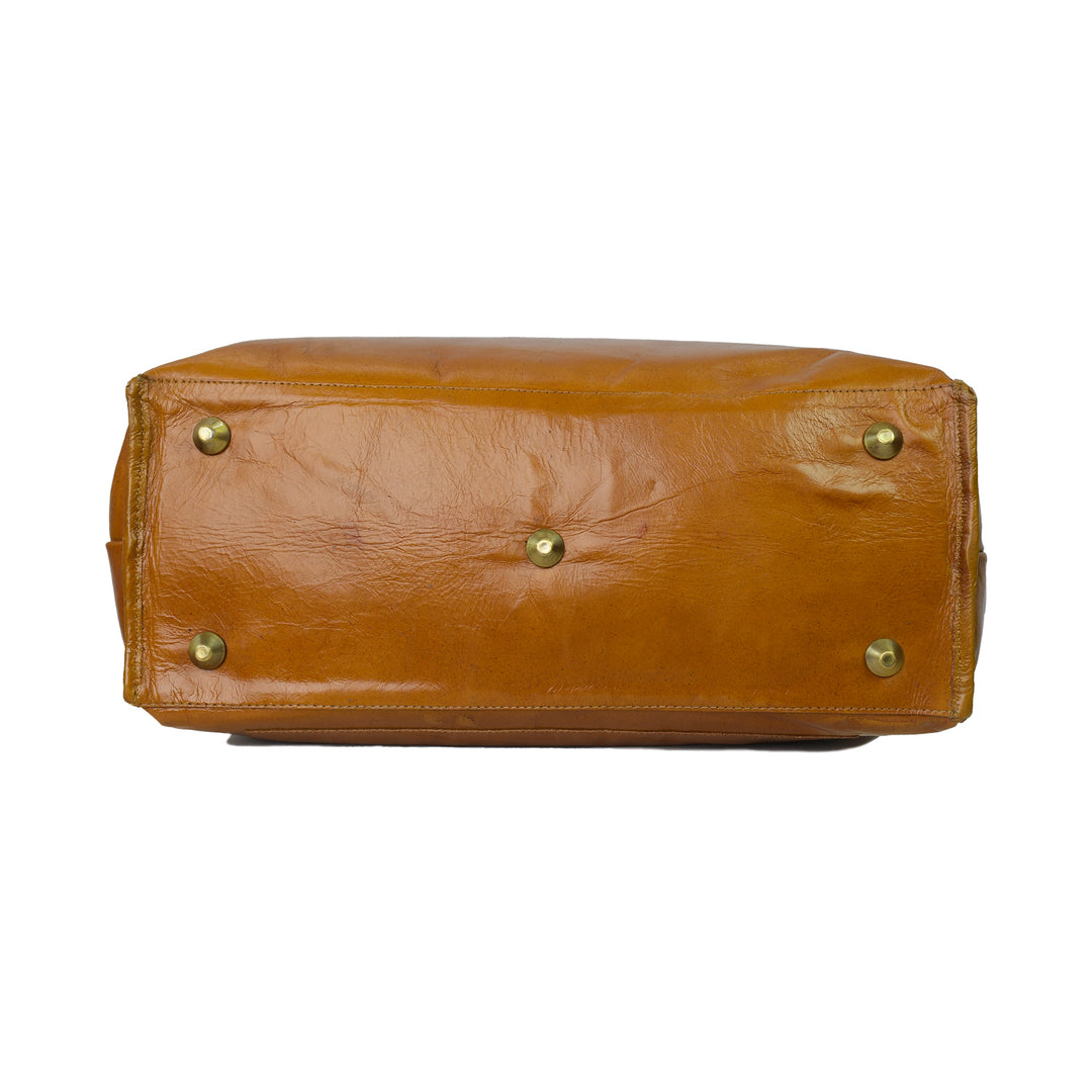 Brown leather bag with gold studs on a white background
