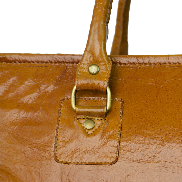 Close-up of a brown leather bag with gold buckle and studs on a white background