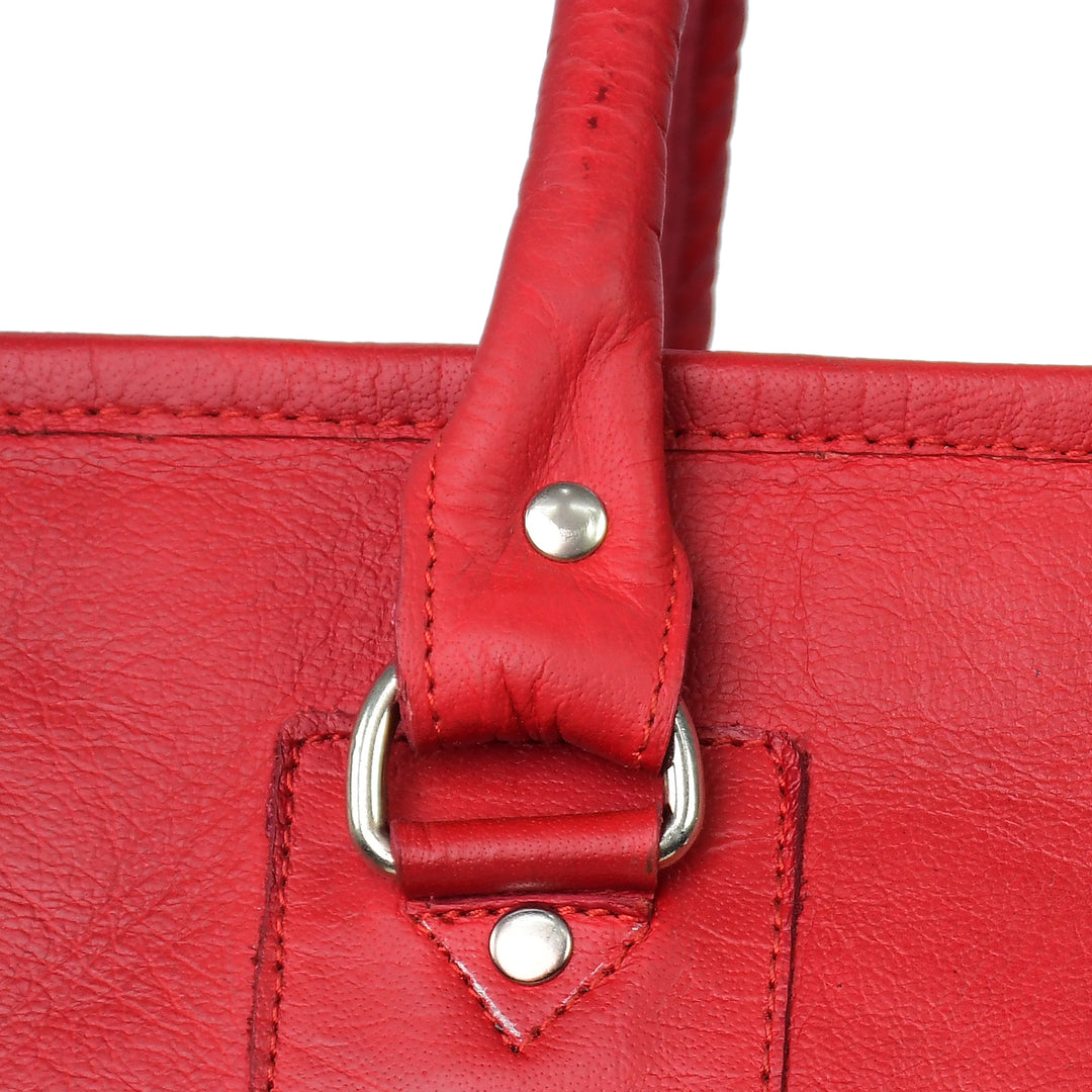 Close-up of a red leather handbag handle with metal hardware on a white background