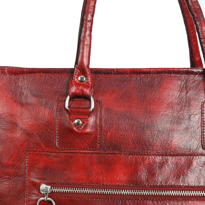 Close-up of a red leather handbag with silver zippers on a white background