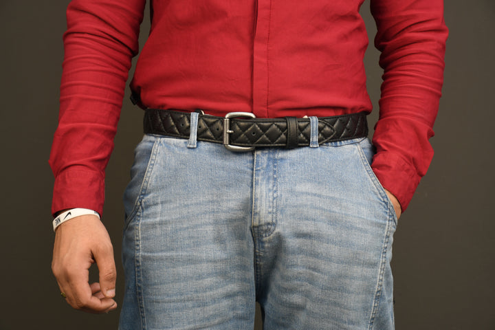 Person wearing a red shirt and blue jeans with a black belt on a dark background