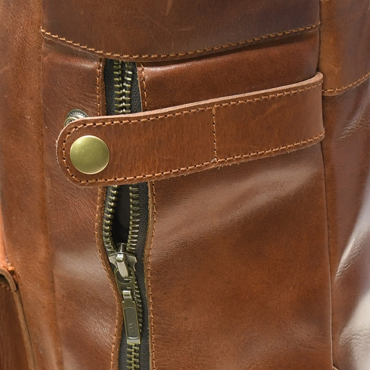 Close-up of a brown leather bag with a zipper and button detail.