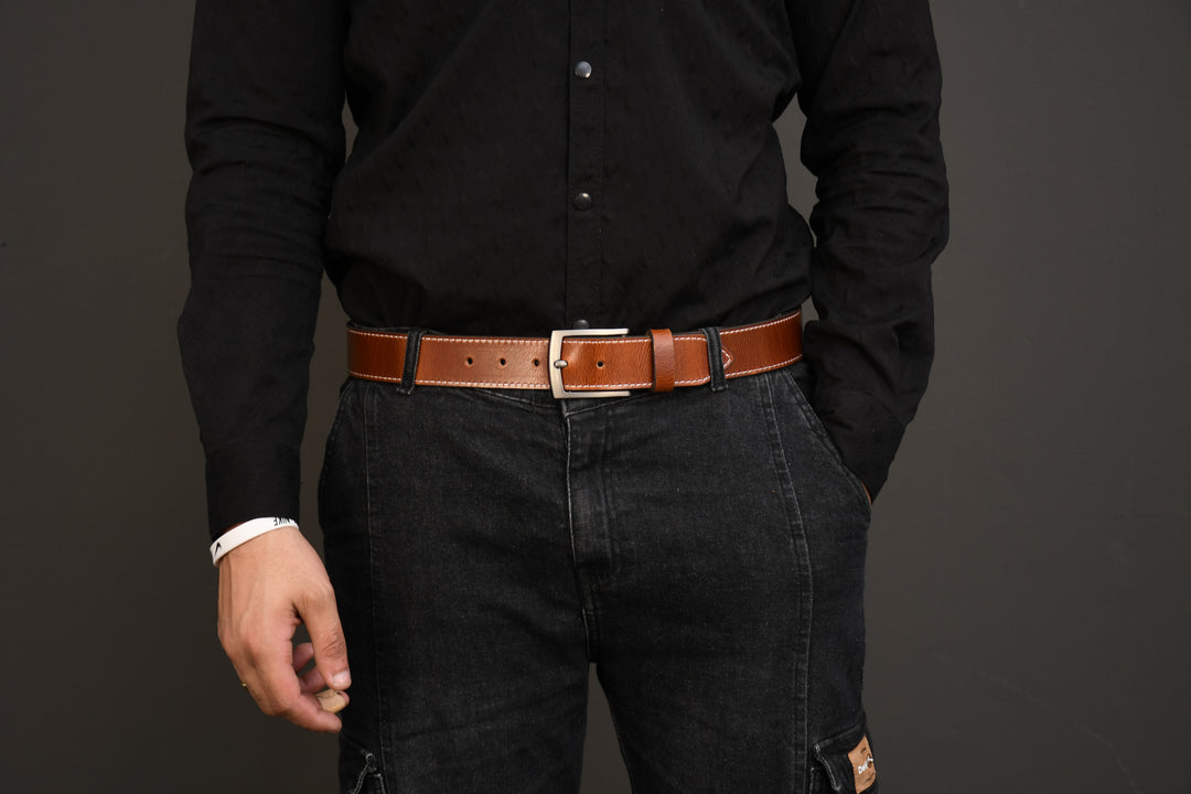 Person wearing a black shirt and dark jeans with a brown belt on a gray background