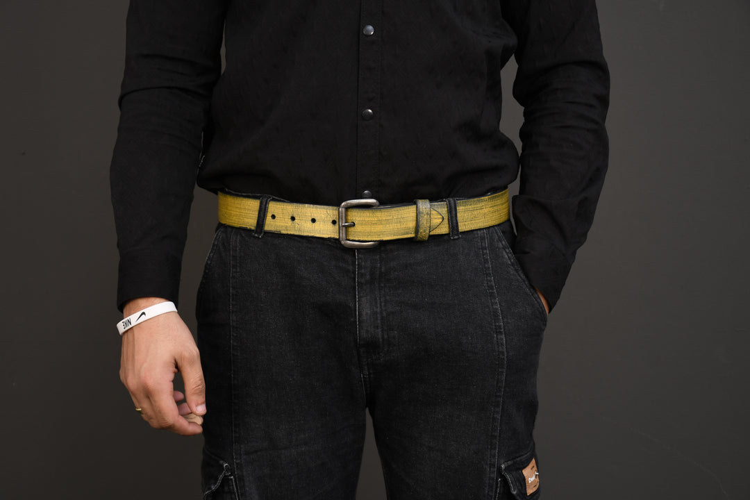 Person wearing a black shirt, black pants, and a yellow belt on a dark background