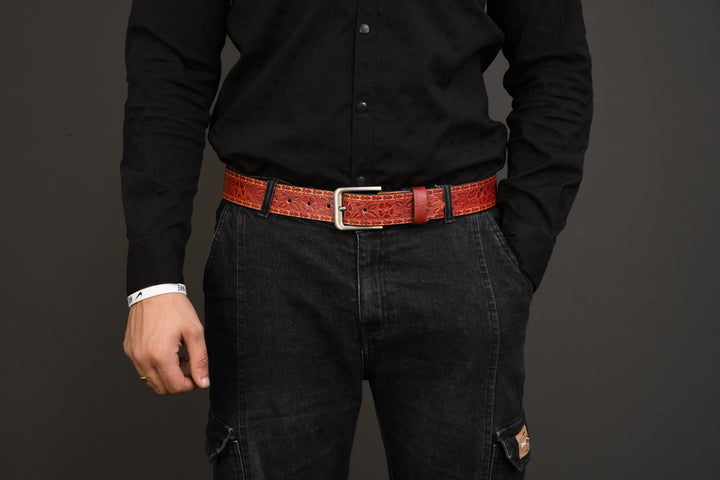 Person wearing a black shirt and dark jeans with a red belt on a gray background