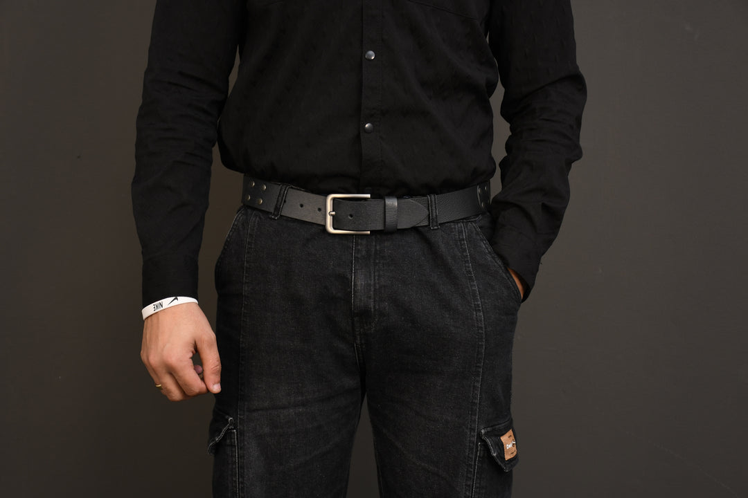 Person wearing a black shirt and pants with a belt on a dark background