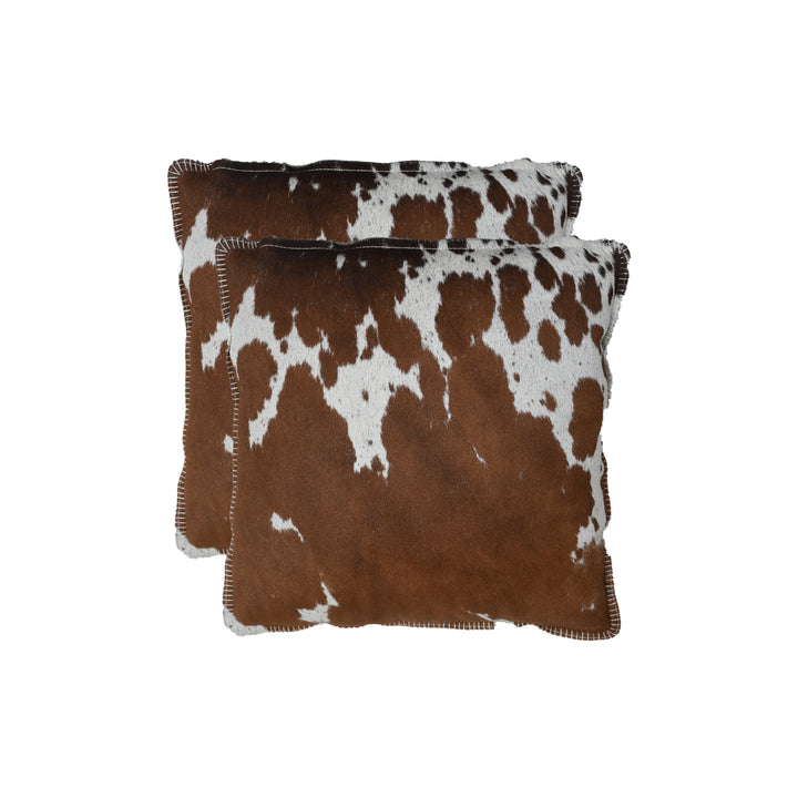 Two brown and white cowhide patterned pillows on a white background