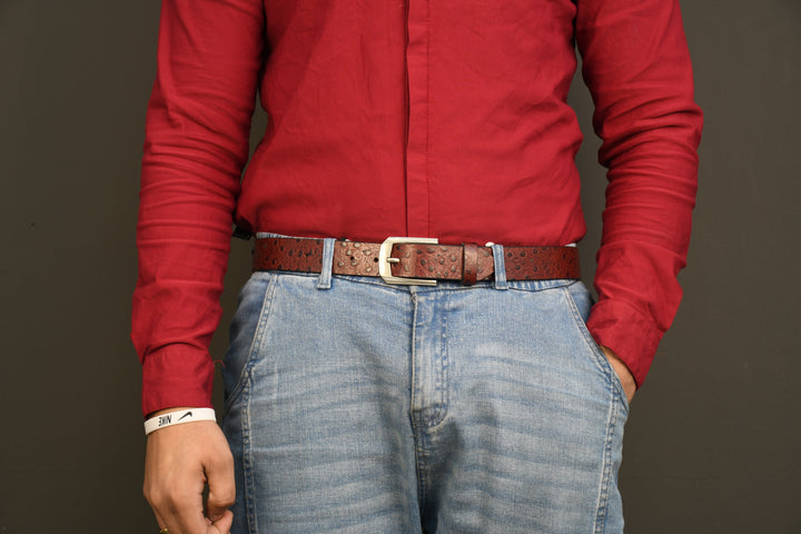 Person wearing a red shirt and blue jeans with a brown belt against a dark background