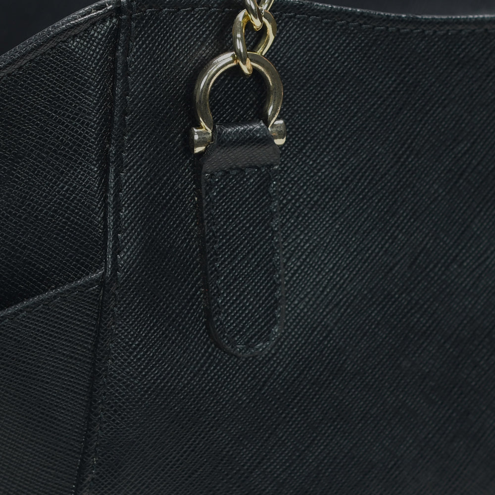 Close-up of a black textured handbag with a gold chain handle.