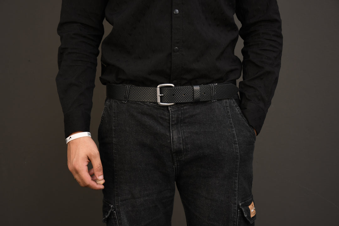 Person wearing a black shirt and dark pants against a gray background