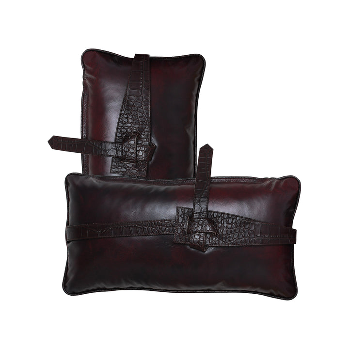 Two dark brown leather pillows with crocodile texture on a white background