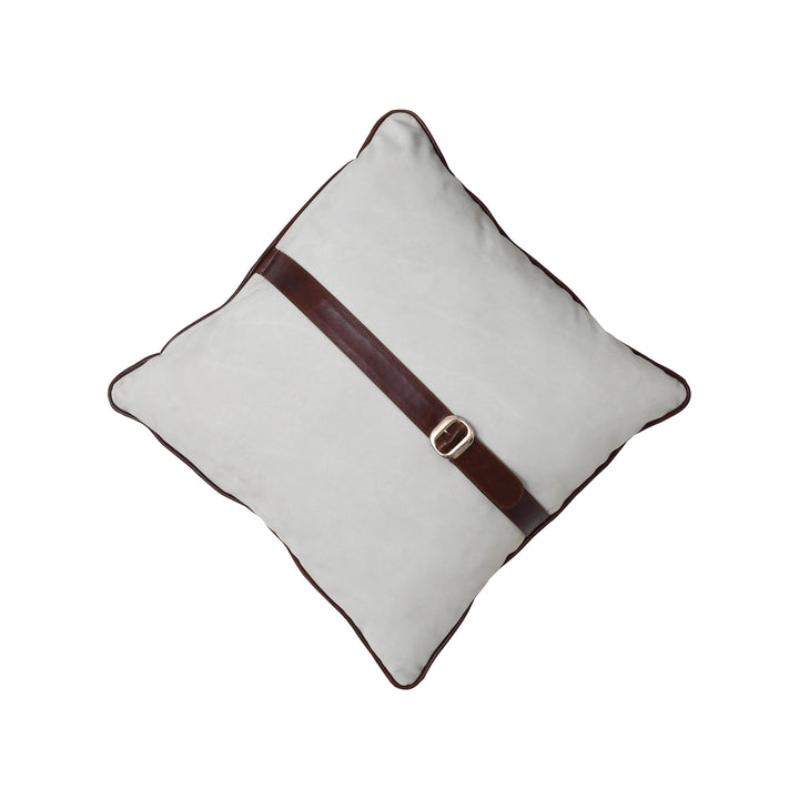 White pillow with a brown leather strap and gold buckle on a white background