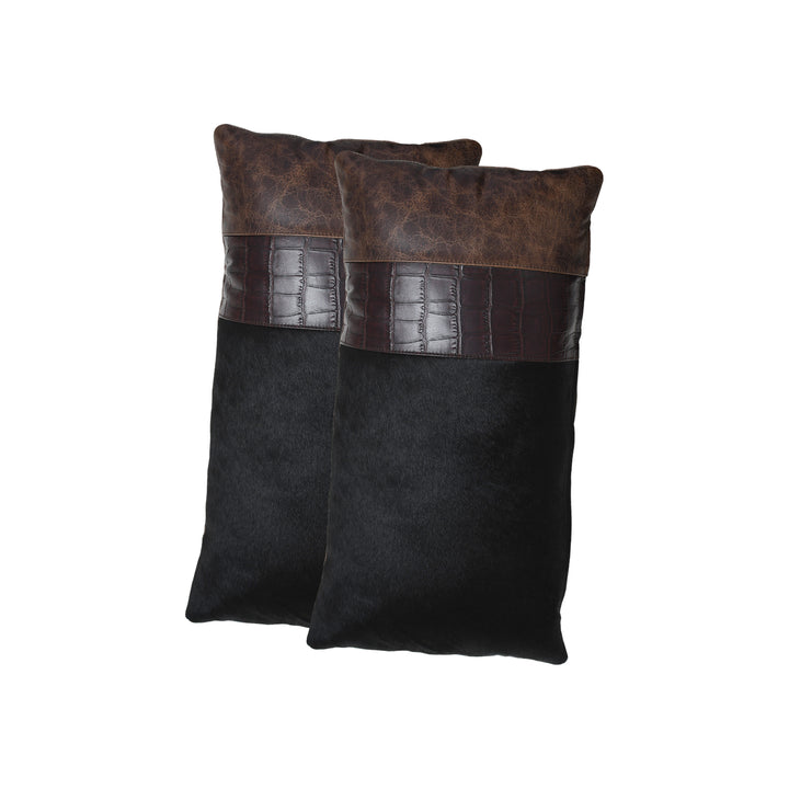 Two black pillows with brown leather accents on a white background