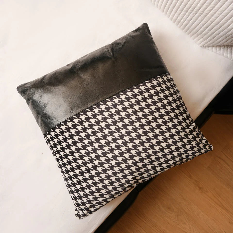 Black and white patterned pillow on a white sofa with wooden floor.