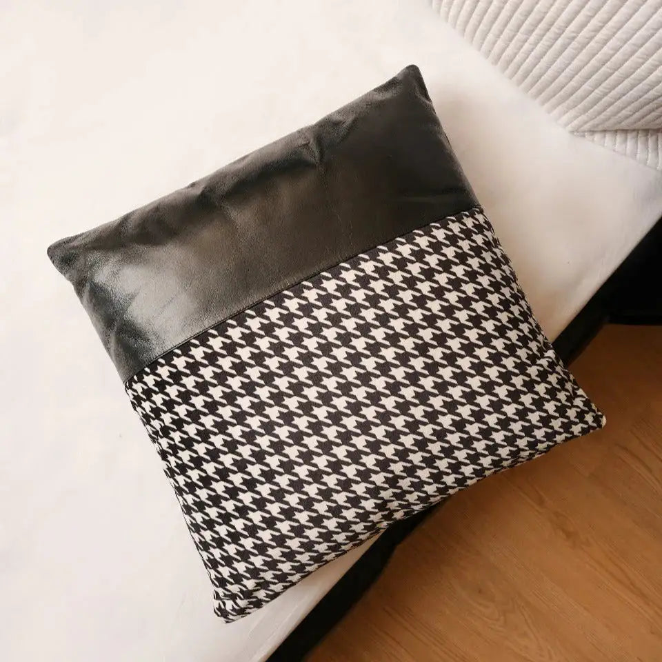 Black and white patterned pillow on a white sofa with wooden floor.