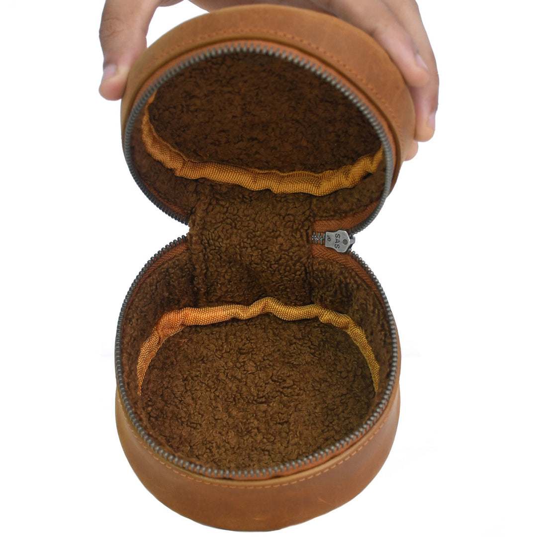Brown leather case with a textured interior held by a hand on a white background