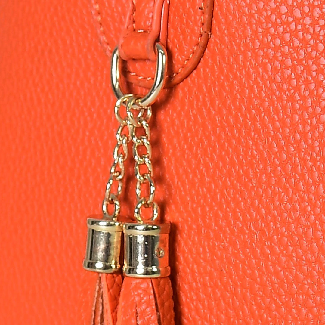 Close-up of a red handbag with a gold chain and spool charm on an orange background