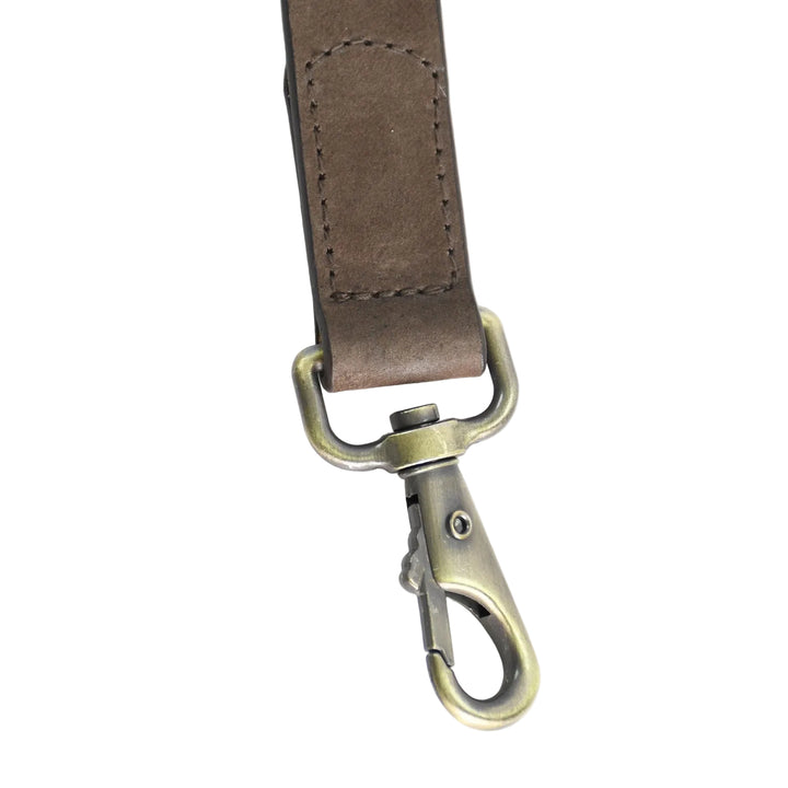 Brown leather strap with brass clasp on a white background

