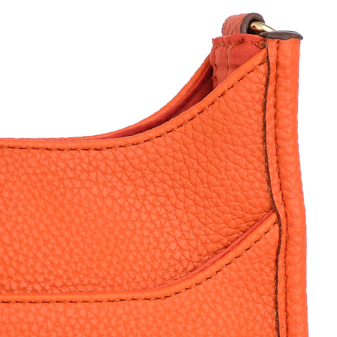 Close-up of an orange leather bag with a gold zipper on a white background