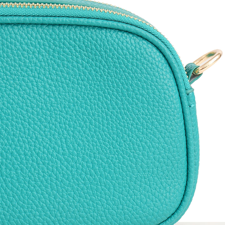 Close-up of a teal handbag with a gold zipper on a white background
