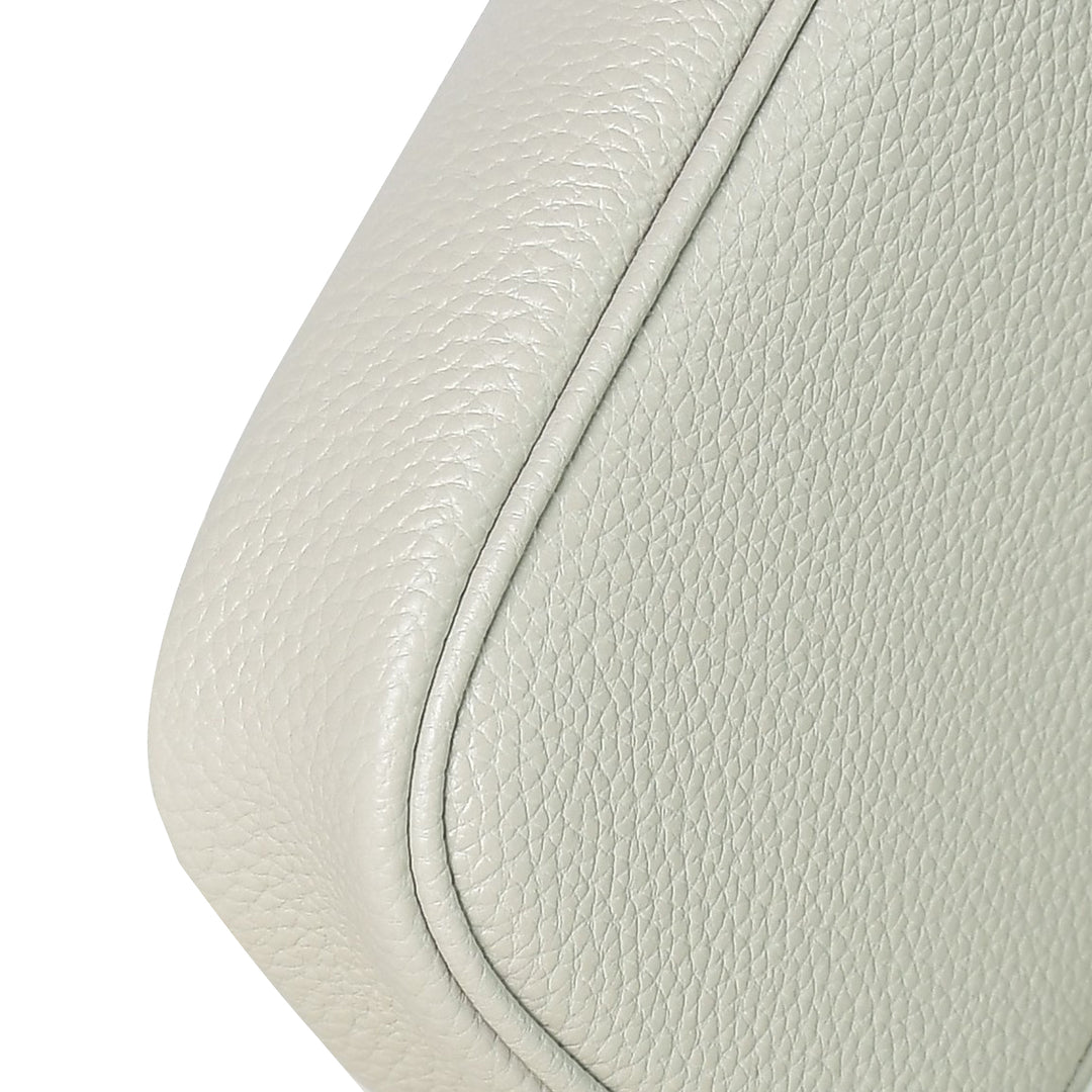 Close-up of a light gray leather seat with stitching detail on a white background