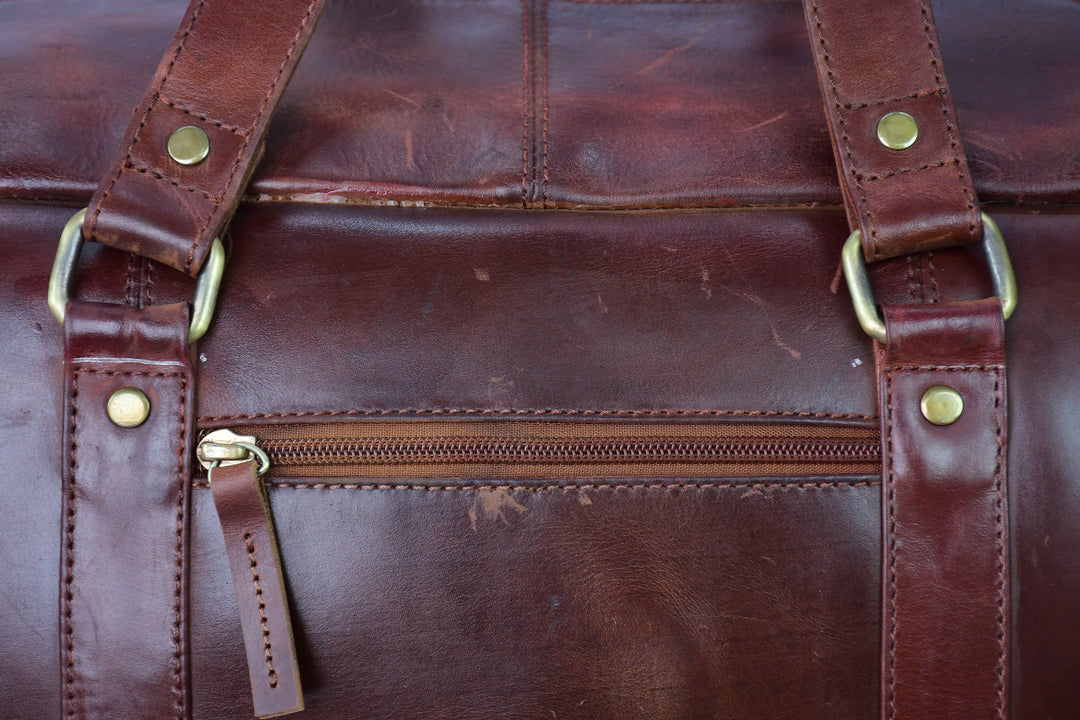 Close-up of a brown leather bag with gold zipper and hardware.