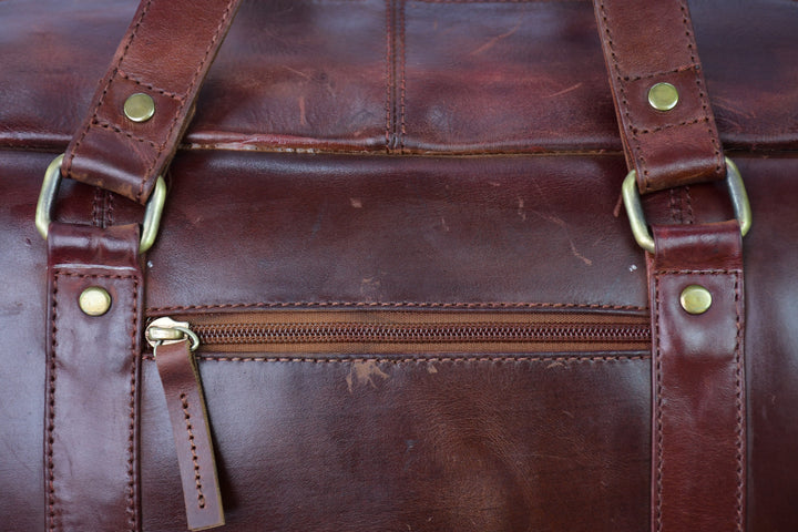 Close-up of a brown leather bag with gold zipper and hardware.