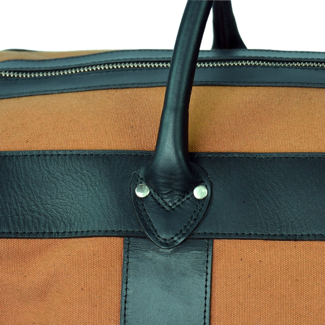 Close-up of a brown and black bag with a leather handle on a white background