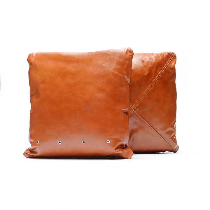 Two brown leather cushions on a white background