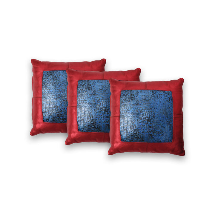 Three red pillows with blue textured centers on a white background

